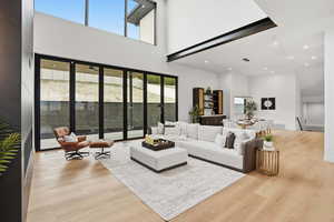 Living room featuring light wood-style floors, recessed lighting, and a high ceiling