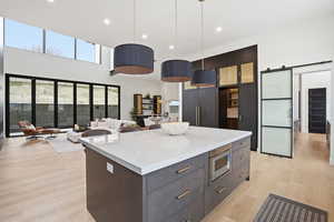 Kitchen with modern cabinets, a barn door, a kitchen island, hanging light fixtures, and open floor plan