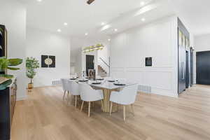 Dining area featuring light wood-type flooring, recessed lighting, and a high ceiling