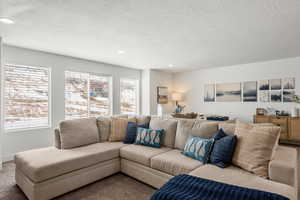 Carpeted living room featuring recessed lighting and a textured ceiling