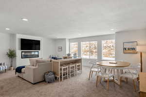Dining room with a textured ceiling, light colored carpet, and recessed lighting