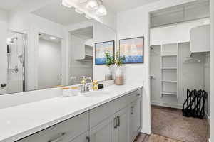 Full bathroom with a walk in closet, vanity, a shower stall, and light wood-type flooring