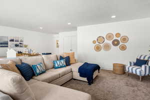 Living area featuring carpet flooring, recessed lighting, and a textured ceiling