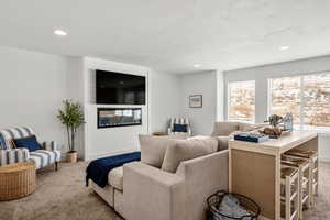 Living room with carpet, a large fireplace, a textured ceiling, and recessed lighting