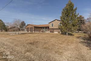 Rear view of house featuring a yard, brick siding, a garage, and driveway