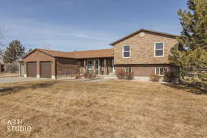 View of front of home featuring a front lawn, driveway, brick siding, and an attached garage