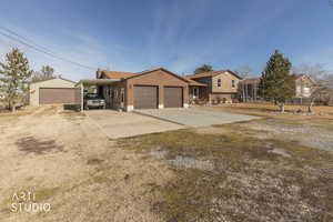 View of front facade with driveway, brick siding, and an outdoor structure