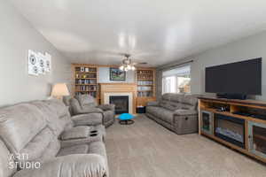Living room featuring a tiled fireplace, a textured ceiling, a ceiling fan, carpet flooring, and built in features