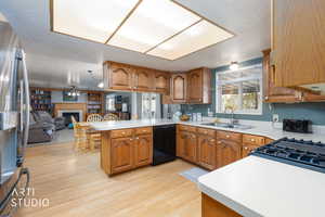 Kitchen with wood finish cabinets, a fireplace, a peninsula, stainless steel refrigerator with ice dispenser, and a textured ceiling