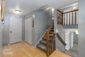 Stairs featuring a textured ceiling and wood finished floors