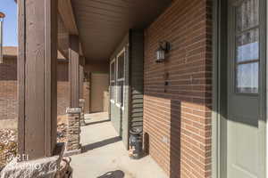 View of exterior entry with covered porch and brick siding