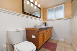 Bathroom featuring a wainscoted wall, vanity, and light tile patterned flooring