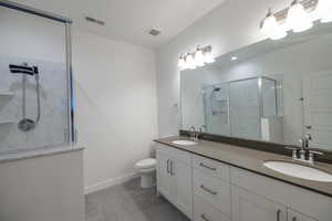 Bathroom with a marble finish shower and double vanity