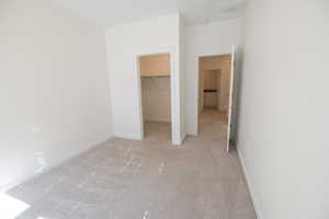 Unfurnished bedroom with a walk in closet and light carpet