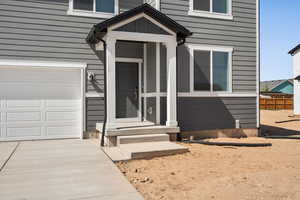 Entrance to property featuring concrete driveway and an attached garage