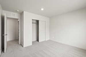 Unfurnished bedroom with light carpet and a closet