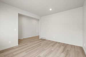 Empty room featuring light wood-style flooring and recessed lighting