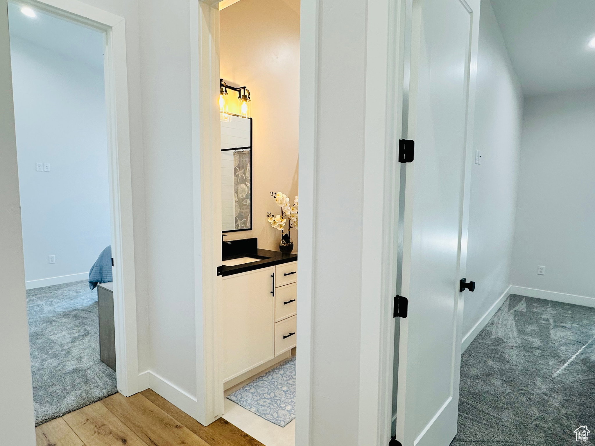 Hallway with light colored carpet, recessed lighting, and light wood-style floors
