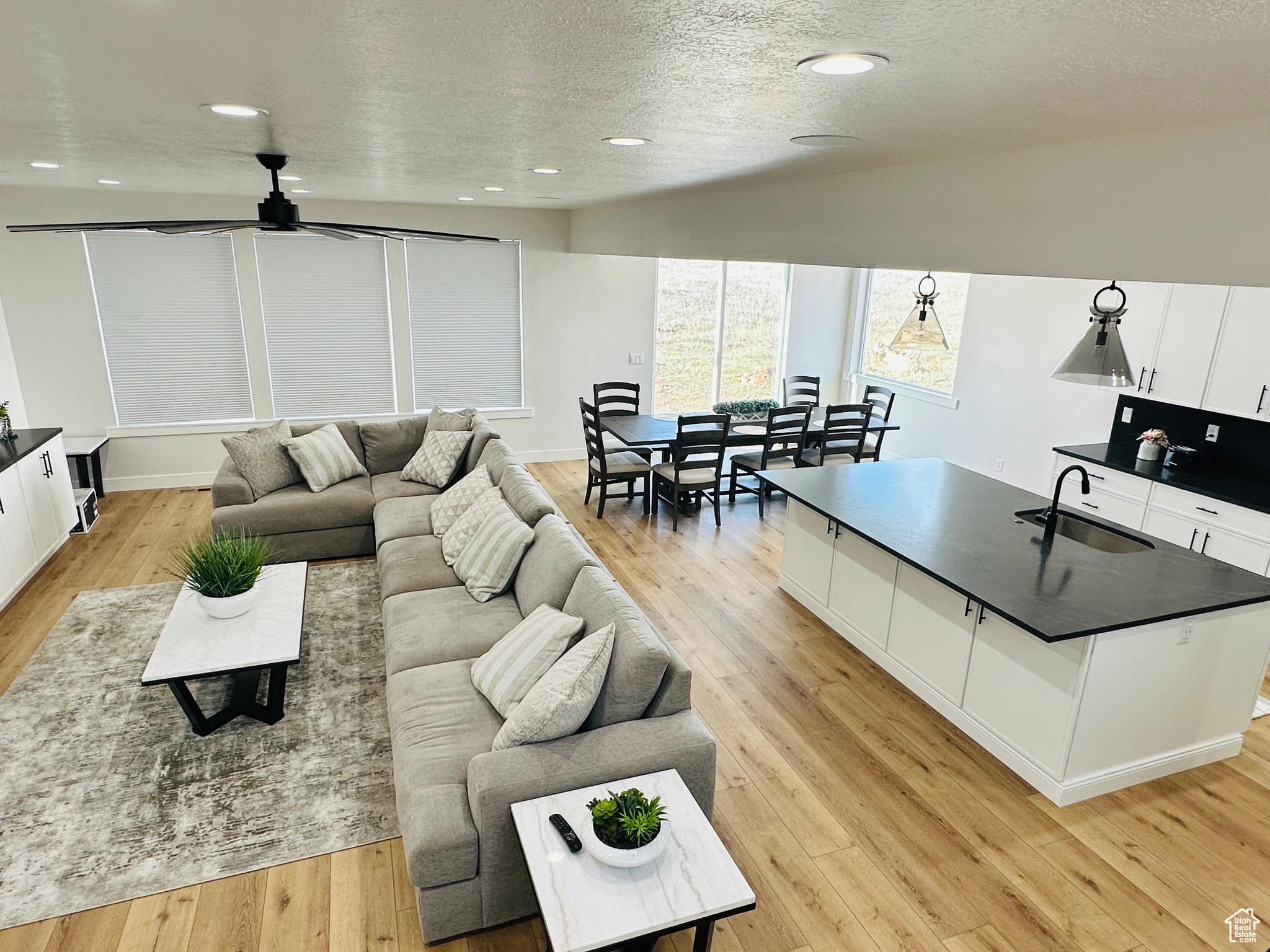 Living area featuring a textured ceiling, light wood-style floors, recessed lighting, and a ceiling fan