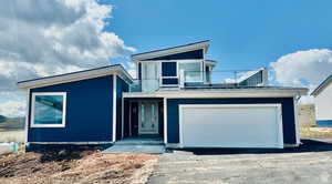 View of front of house with asphalt driveway, a garage, and a standing seam roof
