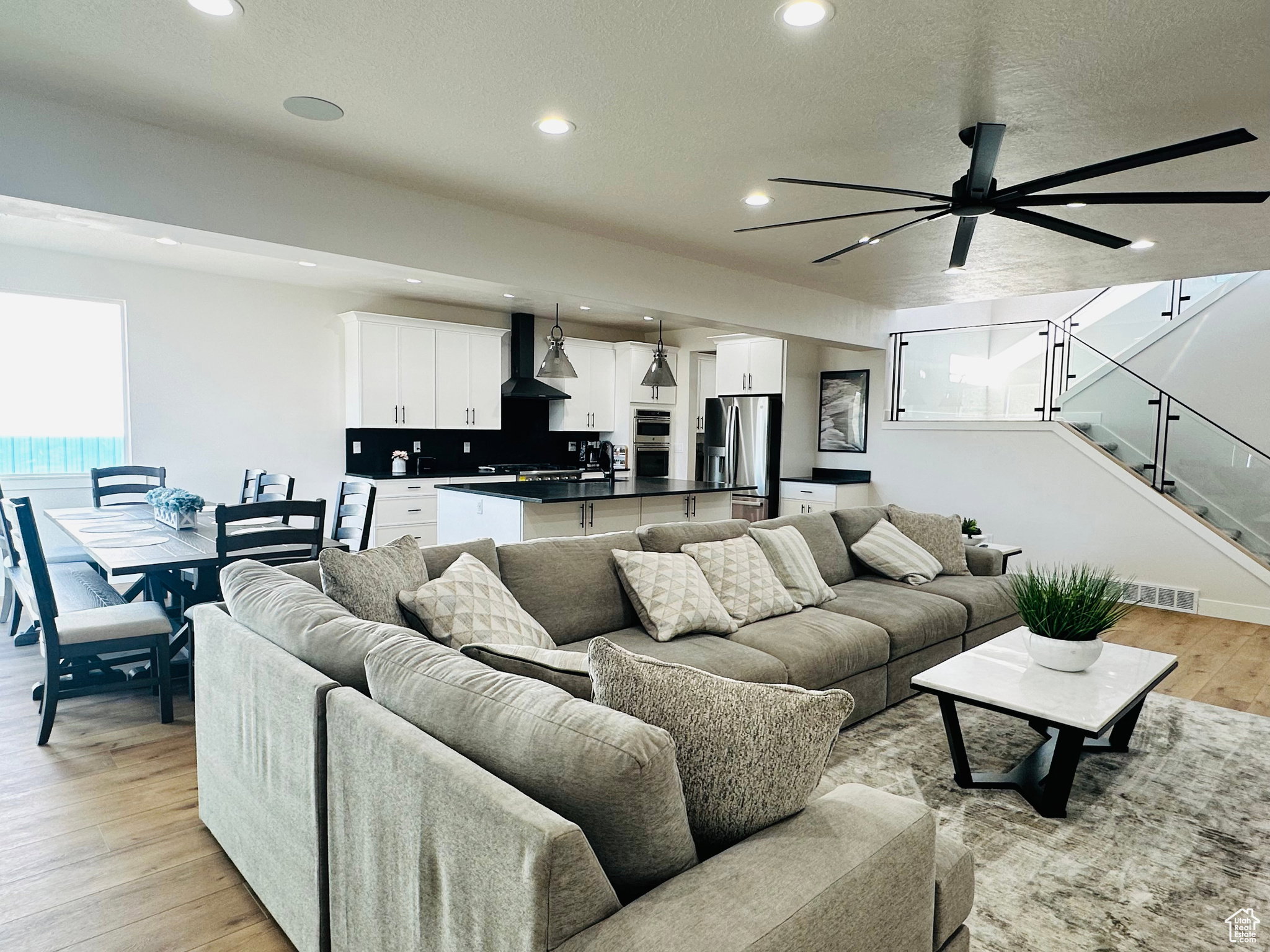 Living area with light wood-type flooring, a ceiling fan, recessed lighting, and a textured ceiling