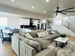 Living area with light wood-type flooring, a ceiling fan, recessed lighting, and a textured ceiling