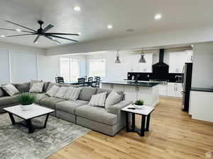 Living room with light wood-type flooring, recessed lighting, a textured ceiling, and ceiling fan