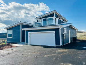 View of front of house featuring an attached garage, driveway, and a balcony