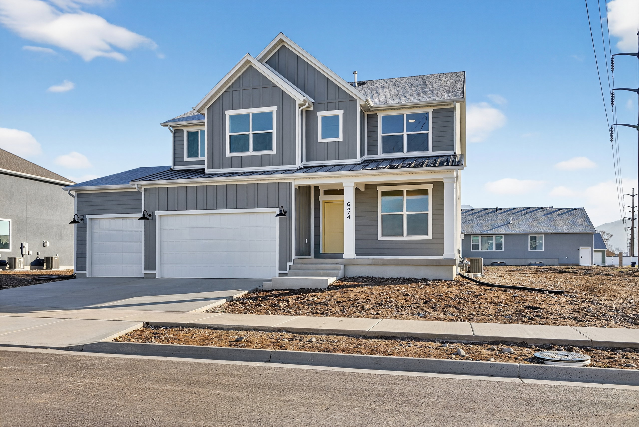 View of front of property with a porch, driveway, board and batten siding, a standing seam roof, and a garage