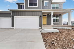 View of front of home with driveway, covered porch, and an attached garage