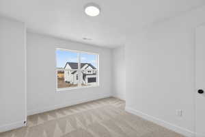 Empty room featuring light colored carpet and a textured ceiling