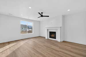 Unfurnished living room with a ceiling fan, a tile fireplace, light wood-type flooring, and recessed lighting