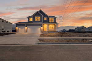 View of front of property with board and batten siding, driveway, covered porch, and an attached garage