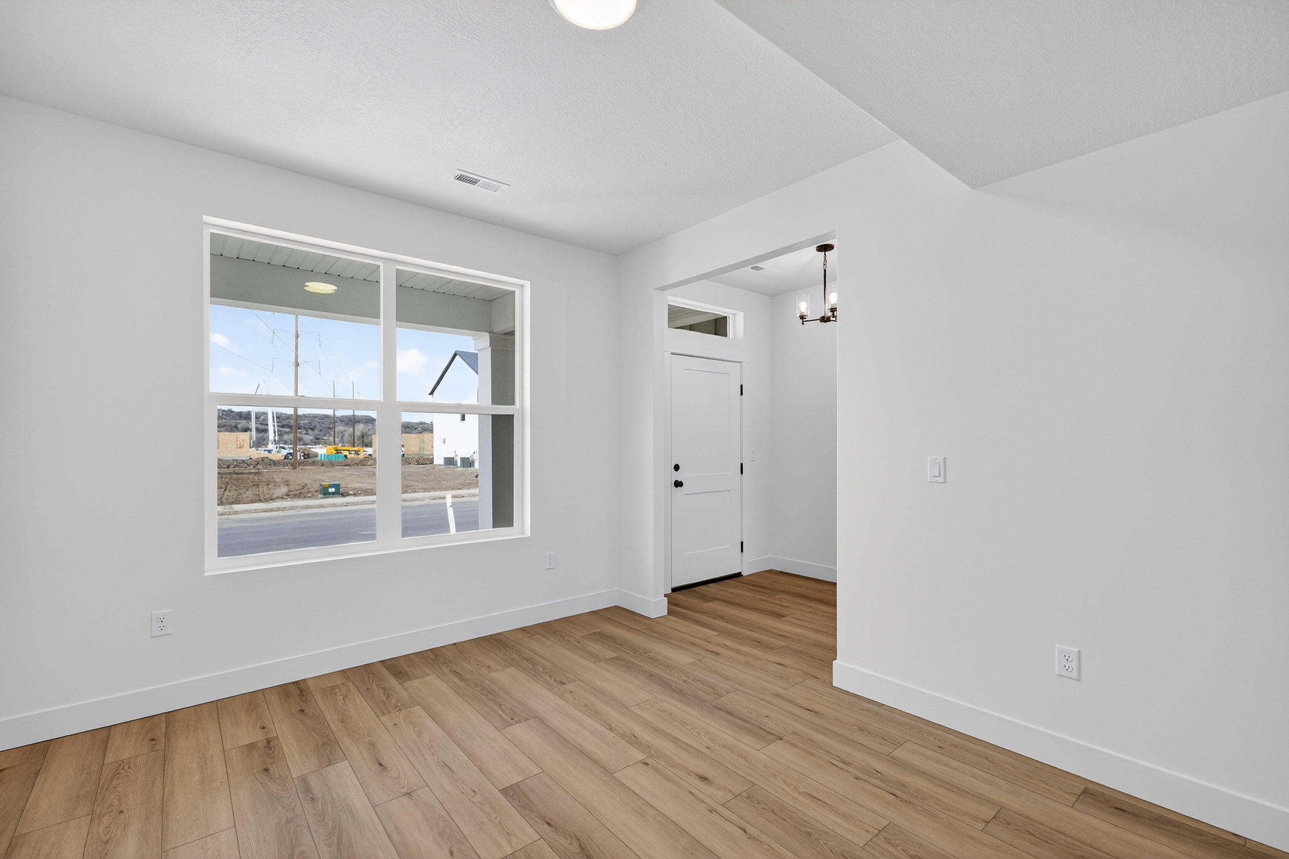 Empty room featuring light wood-type flooring and a chandelier