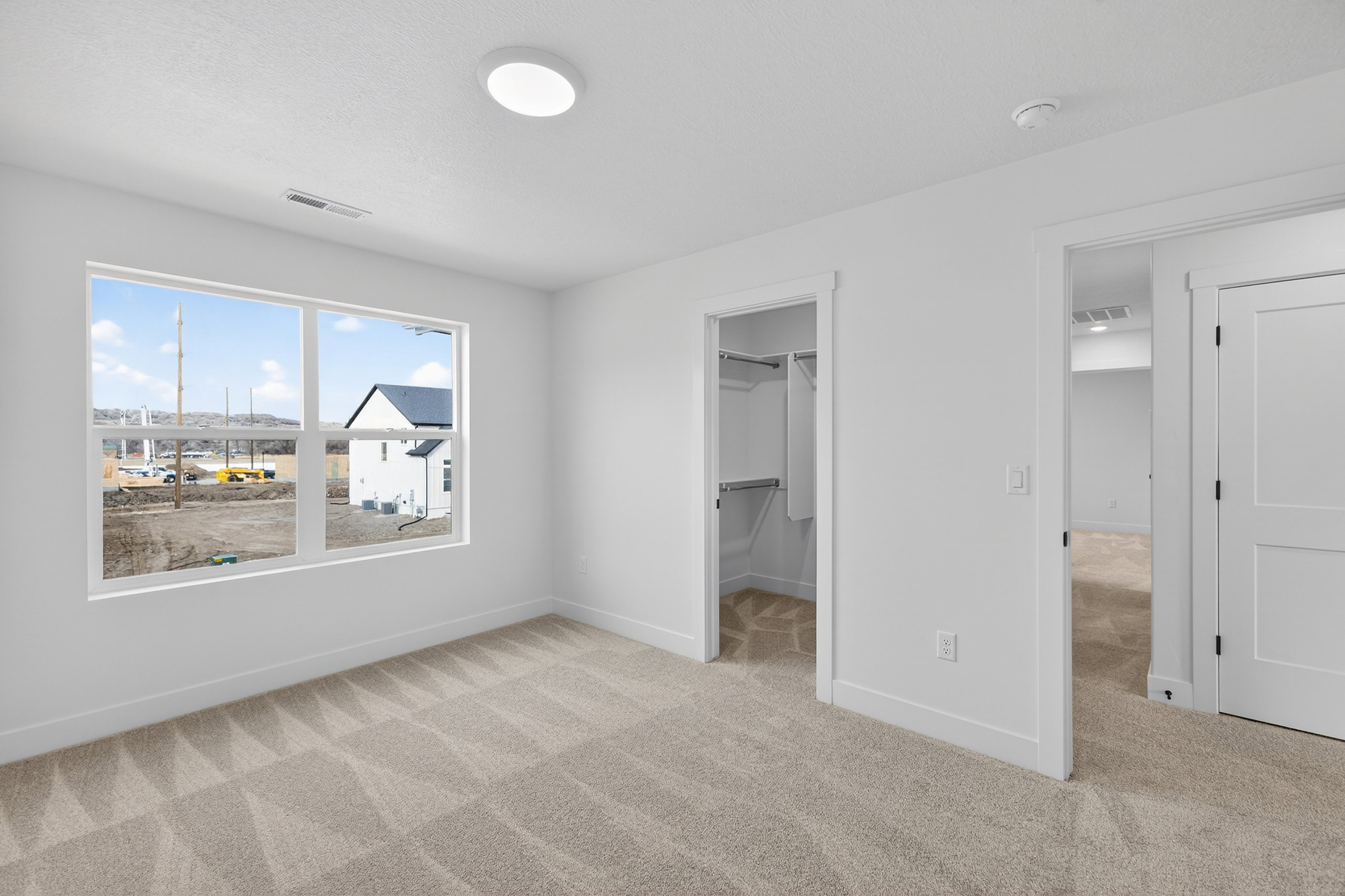 Unfurnished bedroom with light carpet and a spacious closet