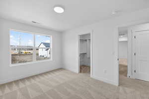 Unfurnished bedroom with light carpet and a spacious closet