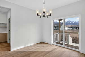 Unfurnished dining area featuring a chandelier, light wood-type flooring, and a mountain view
