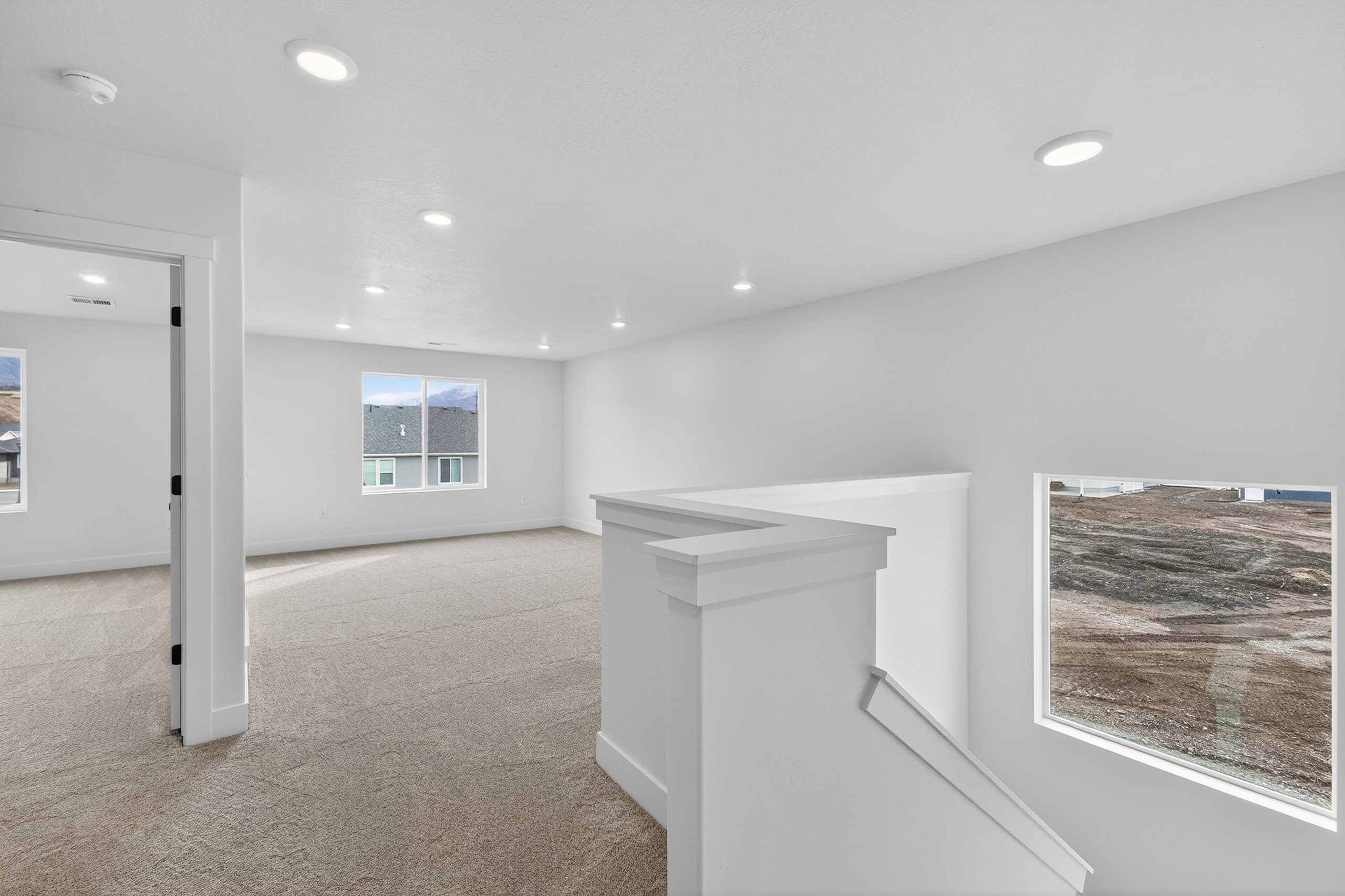 Hall with an upstairs landing, light colored carpet, and recessed lighting