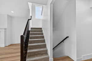 Staircase featuring wood finished floors and recessed lighting