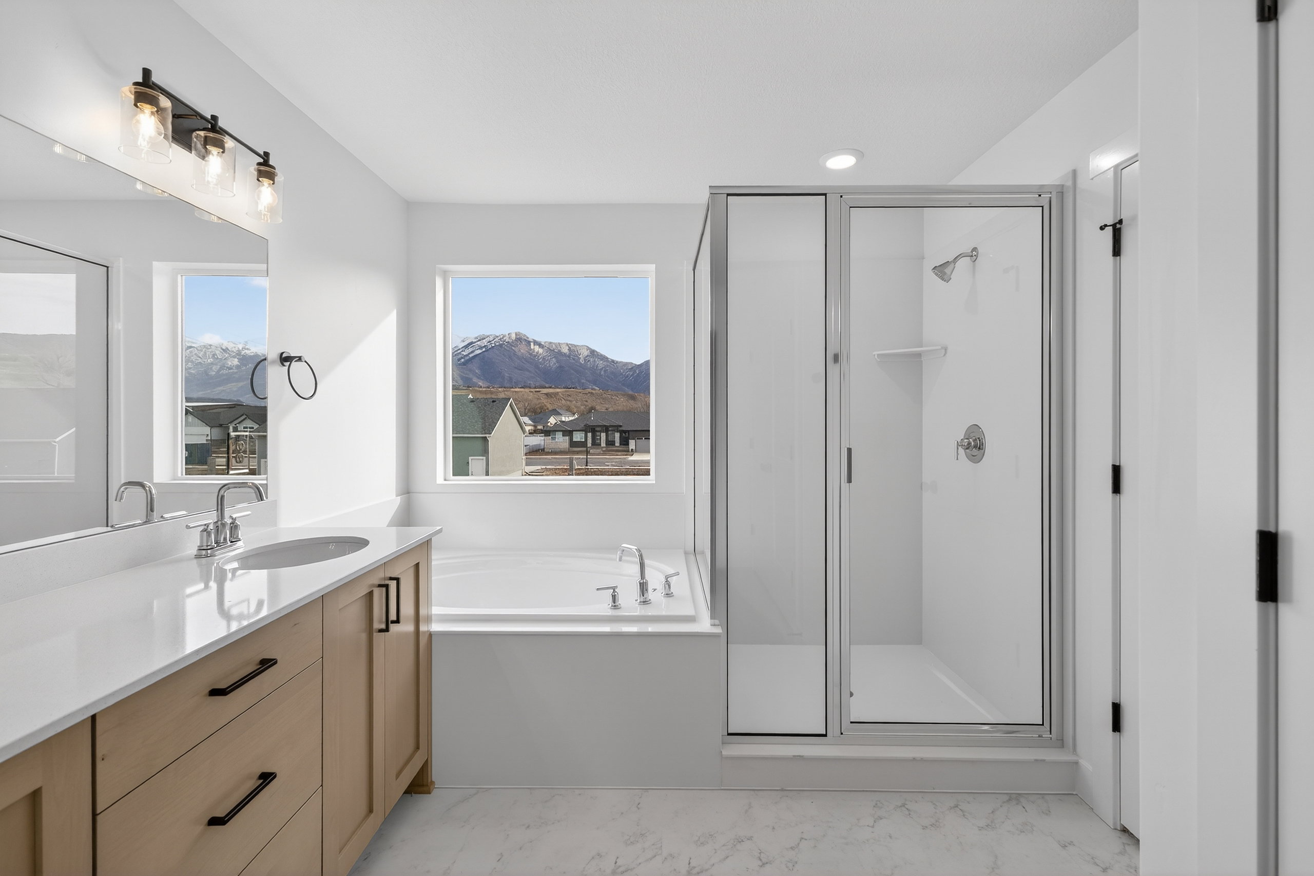 Full bathroom with a shower stall, vanity, a garden tub, a mountain view, and light marble finish flooring