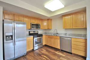 Kitchen with stainless steel appliances, light stone countertops, wood finished floors, and wood finish cabinets