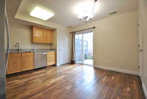 Kitchen featuring stainless steel appliances, two pantries, light stone countertops, a chandelier, and wood-style floors.