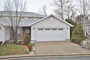 Twin home with a shingled roof, driveway, a garage, and brick and stucco siding
