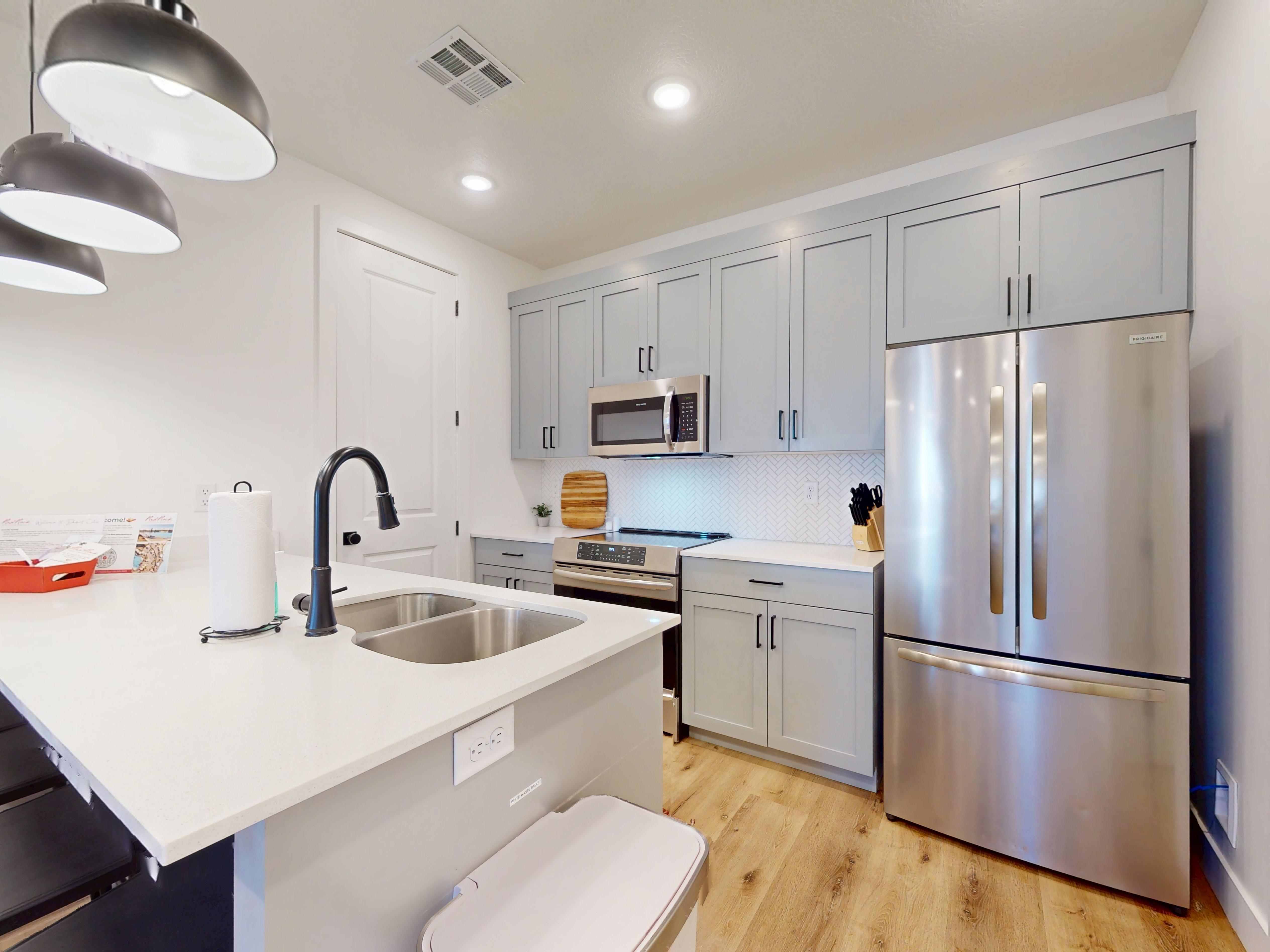 Kitchen featuring stainless steel appliances, gray cabinetry, a kitchen breakfast bar, light wood finished floors, and light stone counters
