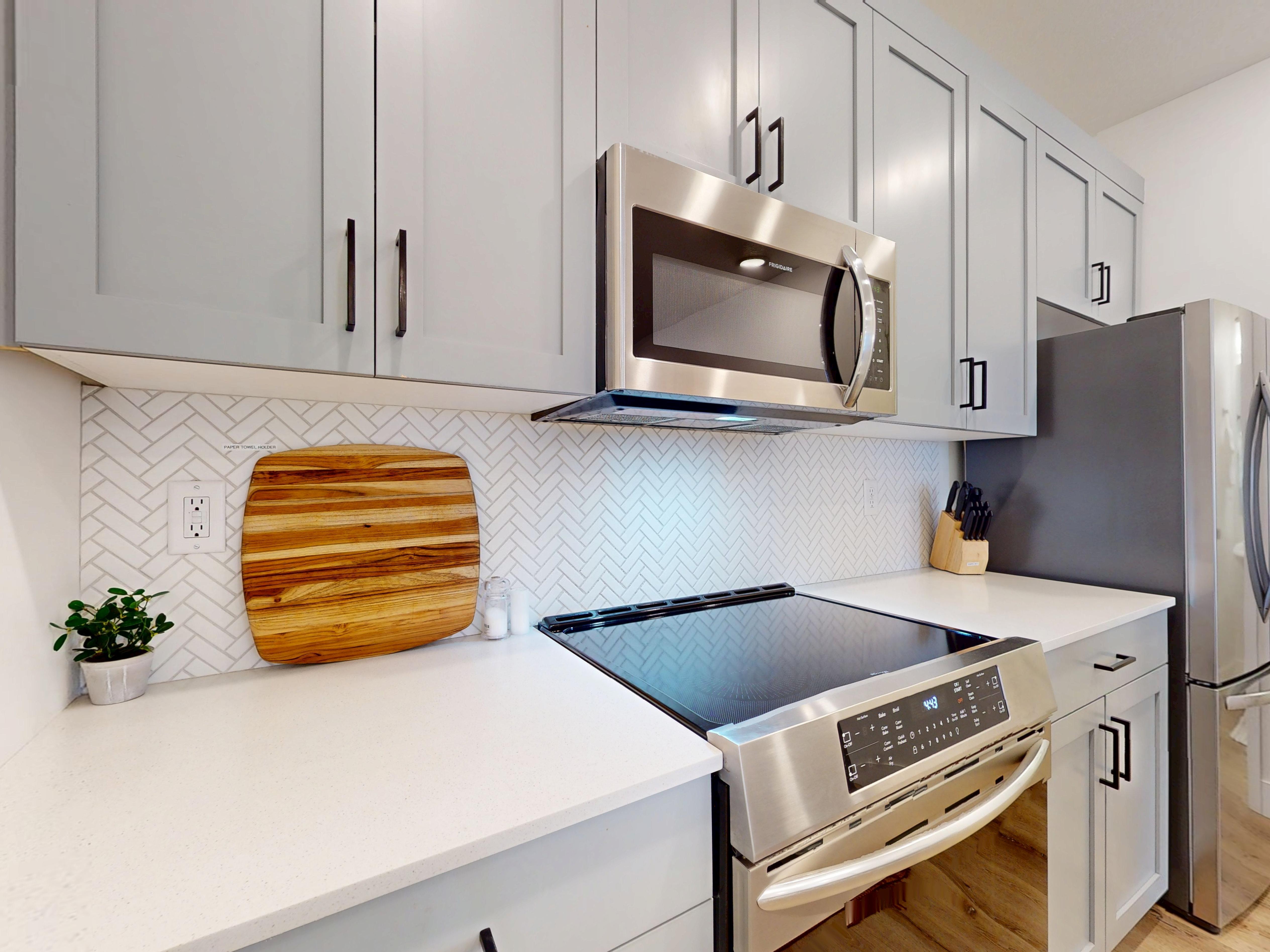 Kitchen with stainless steel appliances, decorative backsplash, light wood finished floors, and light stone countertops