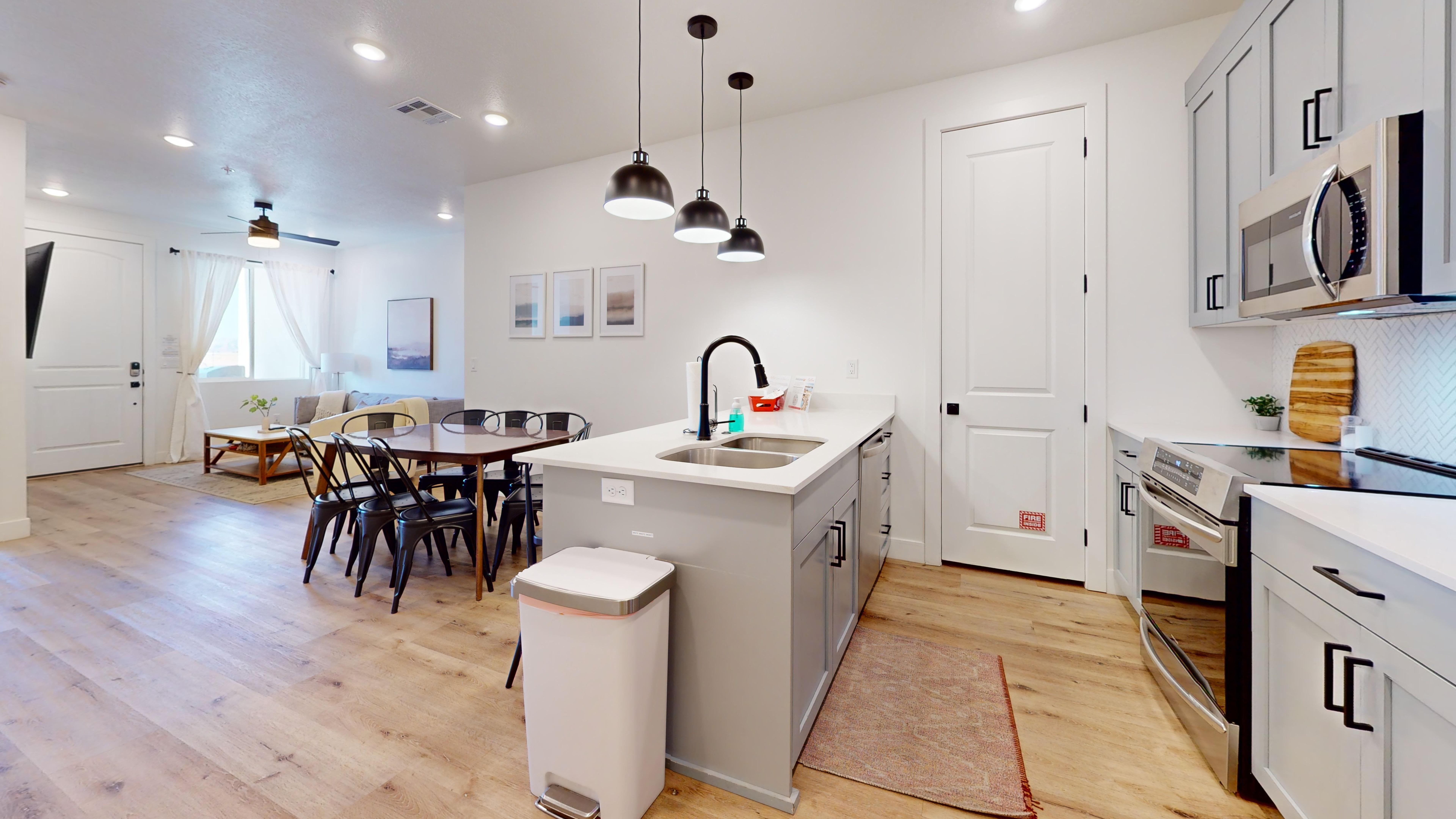 Kitchen with gray cabinets, stainless steel appliances, a peninsula, pendant lighting, and light wood-type flooring