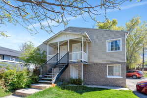 View of front of property featuring stone siding, covered porch, and a front lawn