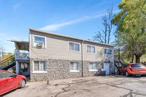 View of front of property with stairway and stone siding