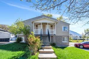 View of front of house featuring stone siding, a front yard, and covered porch