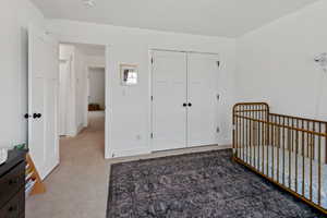 Bedroom with carpet flooring, a crib, and a closet